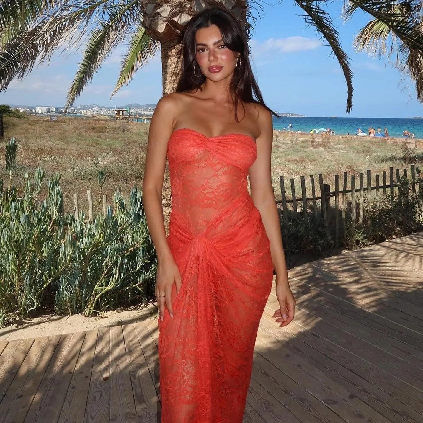 Off-shoulder orange lace maxi dress featuring a fitted bodice and flowing skirt, styled for a beachside outing.