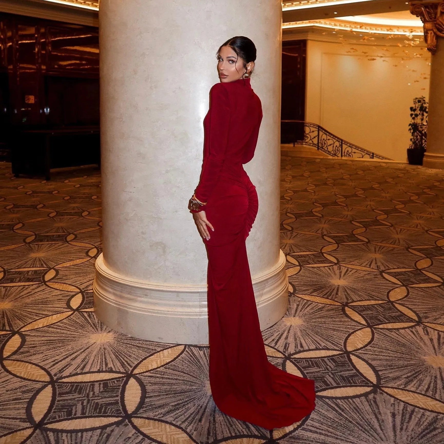 Long sleeve burgundy ruched maxi dress with a fitted silhouette, styled elegantly with a dramatic train.