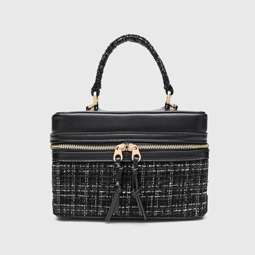 Black textured handbag with gold zipper detailing and top handle.