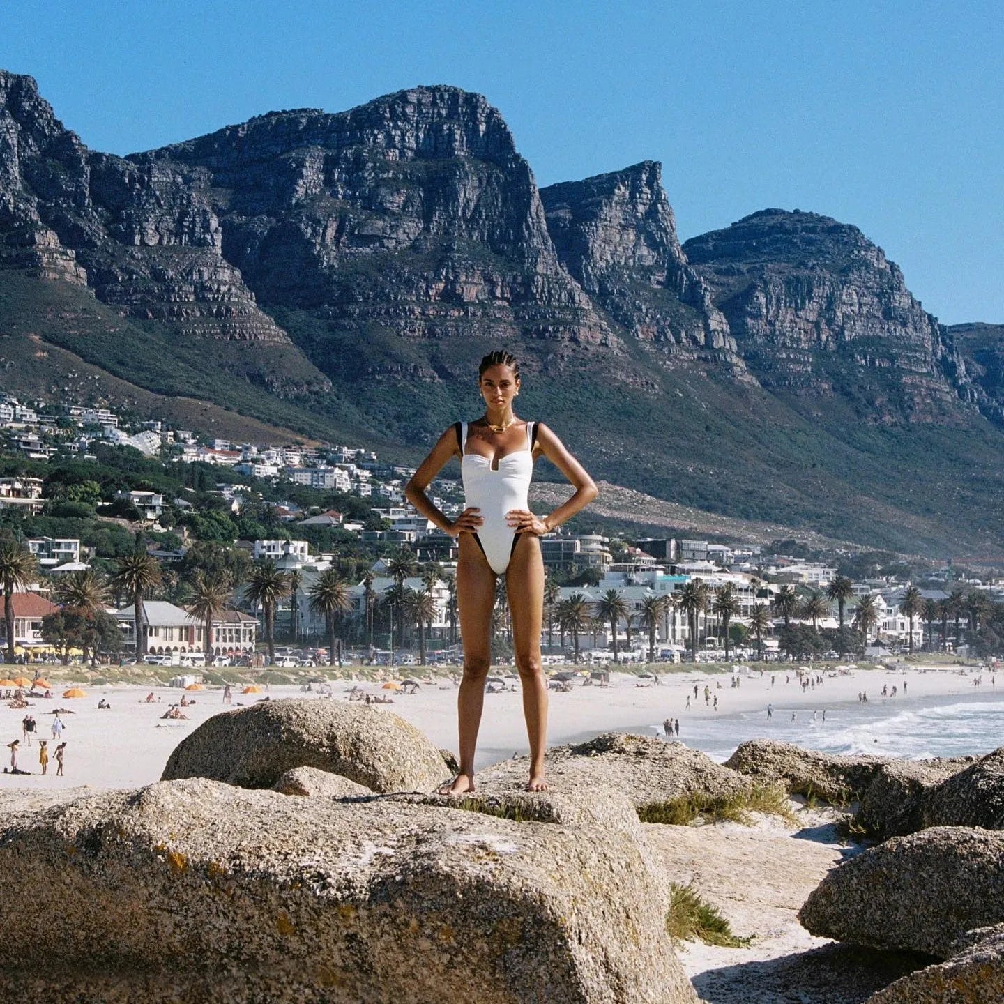 White one-piece swimsuit with contrasting details, styled with minimal accessories, perfect for beach outings.