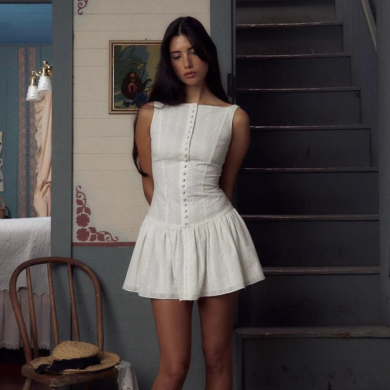 White mini dress featuring delicate embroidery and a button-up front, styled with a flared skirt and fitted bodice.