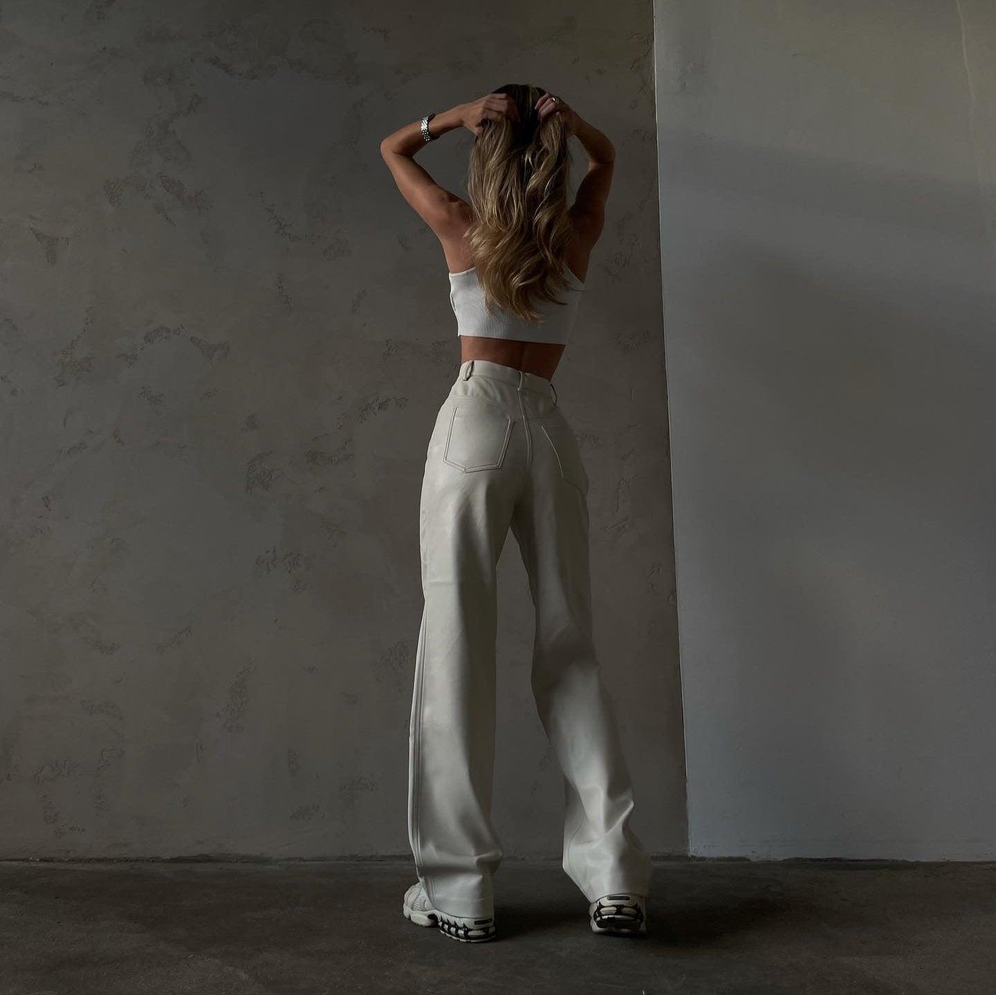 High-waist white leather pants with a flared leg, styled with a fitted crop top for a chic, casual look.