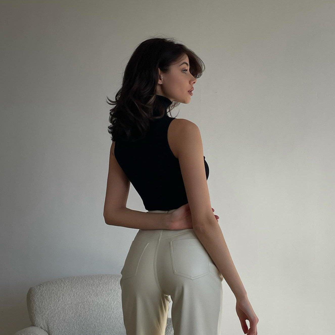 High-waisted white leather pants styled with a fitted black sleeveless top, showcasing a sleek and modern silhouette.