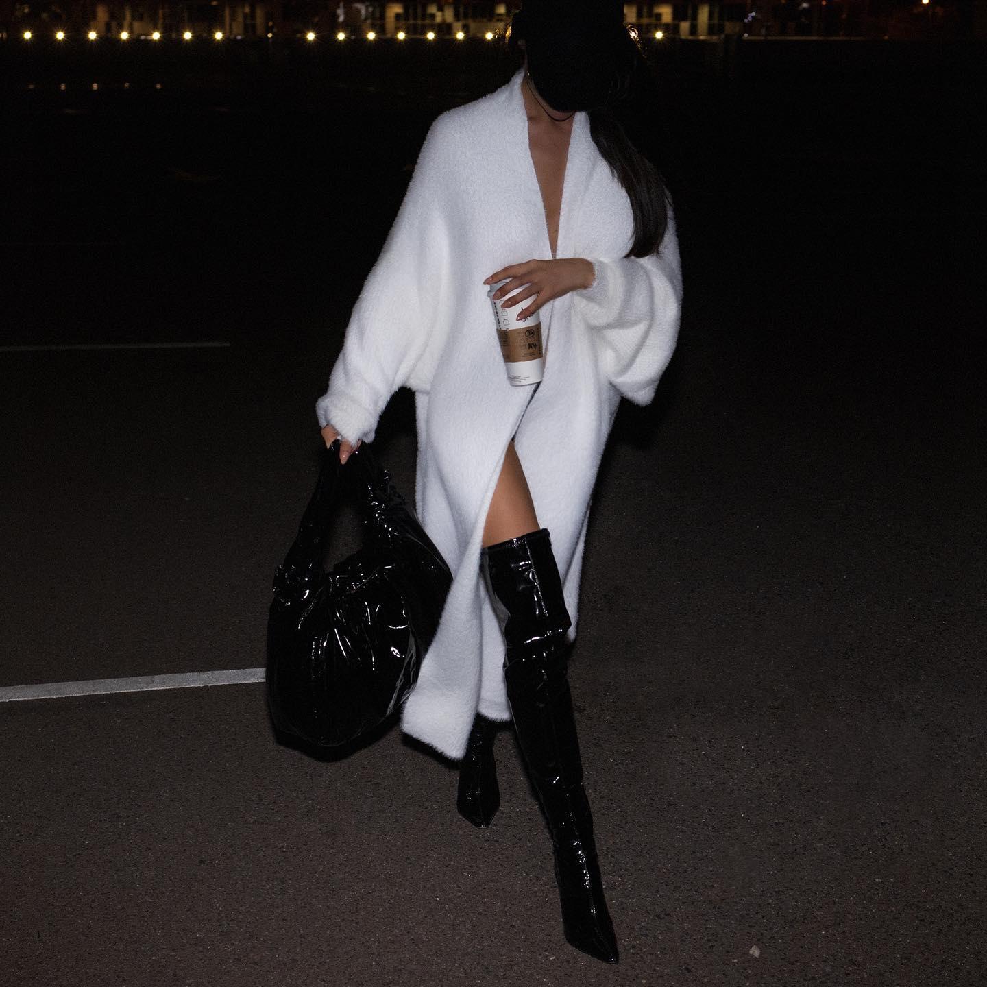 Oversize long sleeve cardigan in misty white, draped open, paired with thigh-high black boots and a chic tote.