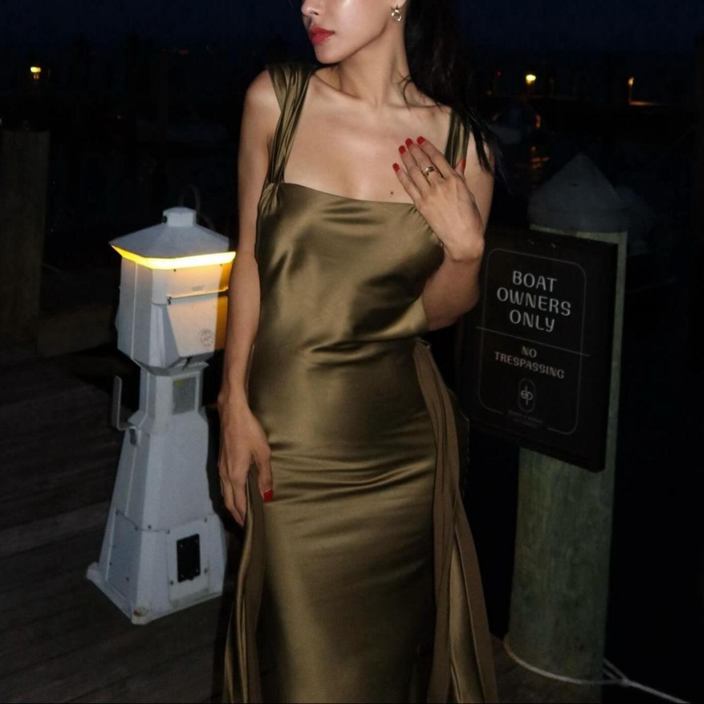 Satin olive maxi dress with sleek straps and side slit, styled elegantly for an evening out.