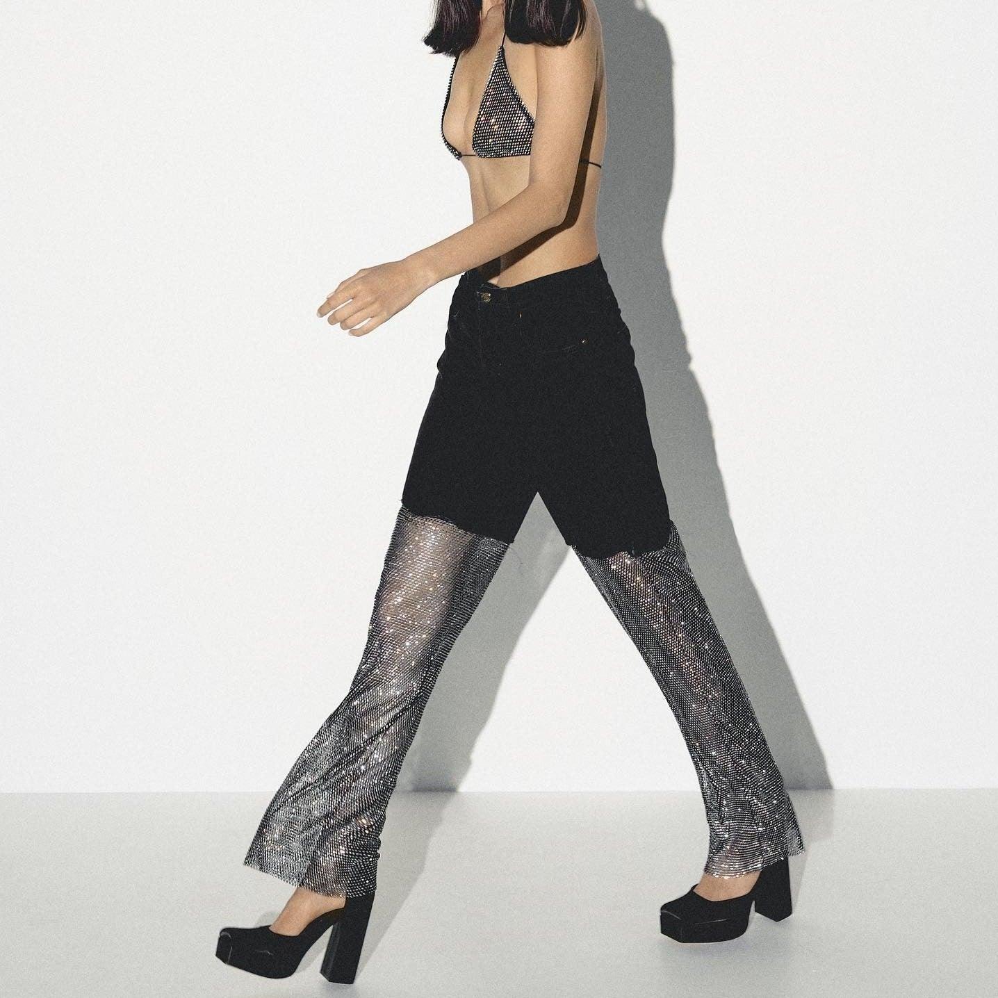 Black diamond mesh jeans with a fitted silhouette, worn with a sparkly bikini top and chunky platform heels.
