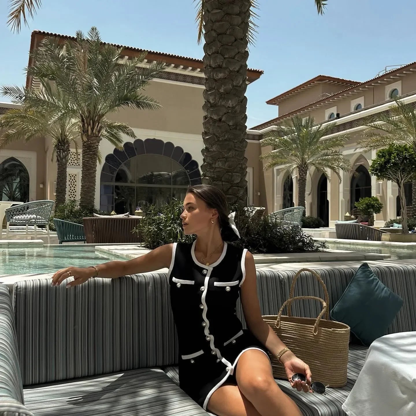 Black sleeveless dress with white trim and button details, perfect for a chic daytime look.