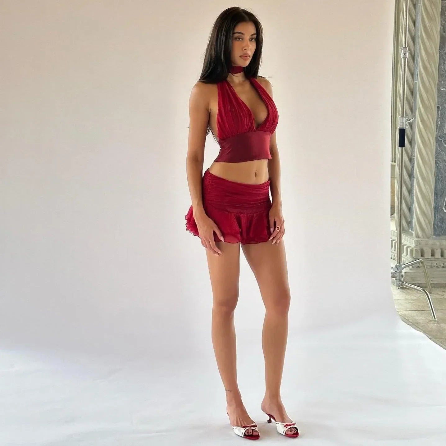 Crimson ruffled two-piece set featuring a halter top and fitted mini skirt, styled with strappy heels for a chic look.