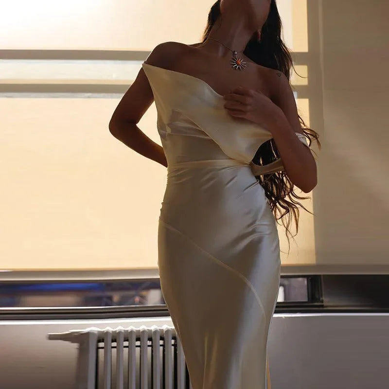 Plunging back cowl maxi dress in soft cream, elegantly draped with off-shoulder styling, perfect for formal occasions.