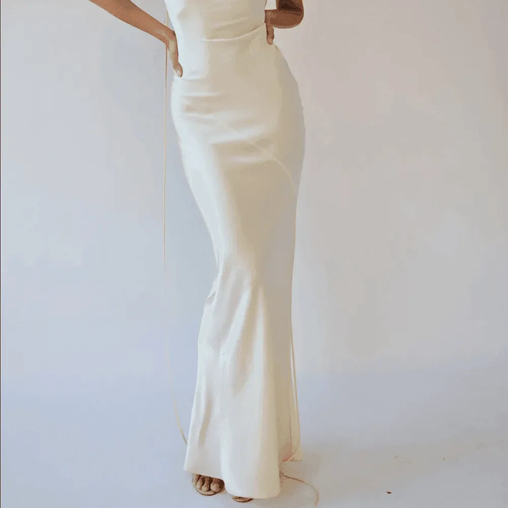 Plunging back cowl maxi dress in cream, featuring a fitted silhouette and flowing skirt, styled elegantly for formal...