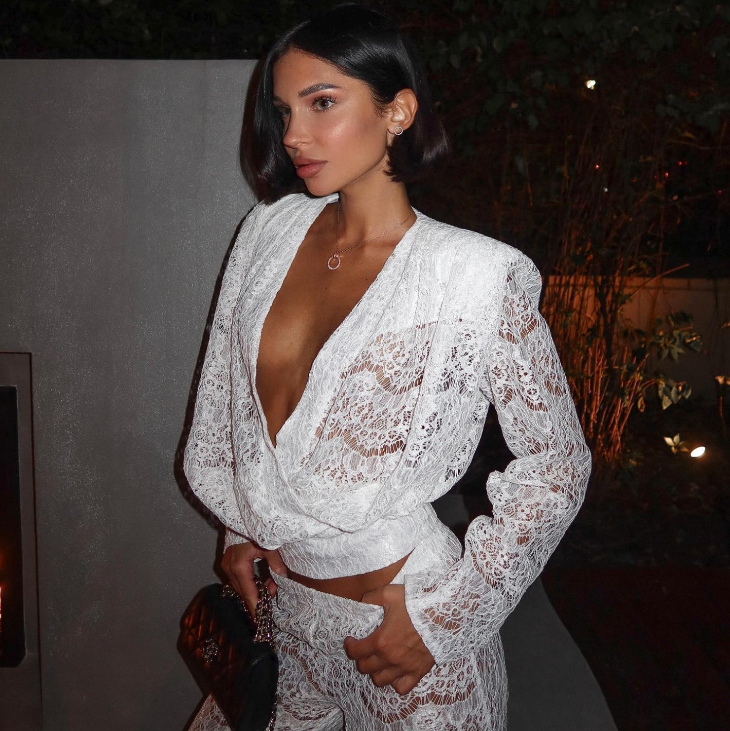 White lace two-piece set featuring a deep V-neck top and high-waisted pants, perfect for an elegant evening look.