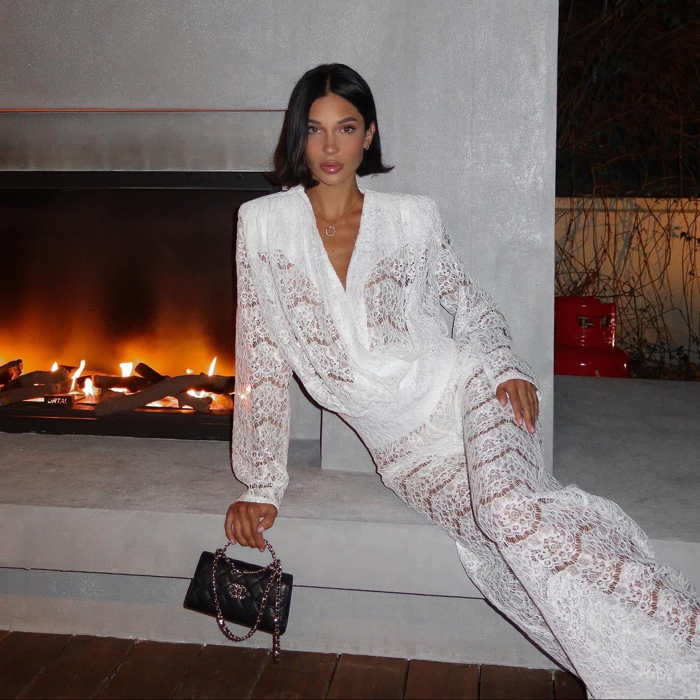White lace two-piece set featuring a v-neck top and wide-leg pants, styled with a chic handbag and minimal accessories.