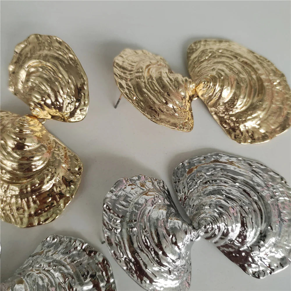 metallic shell-shaped statement earrings in gold and silver