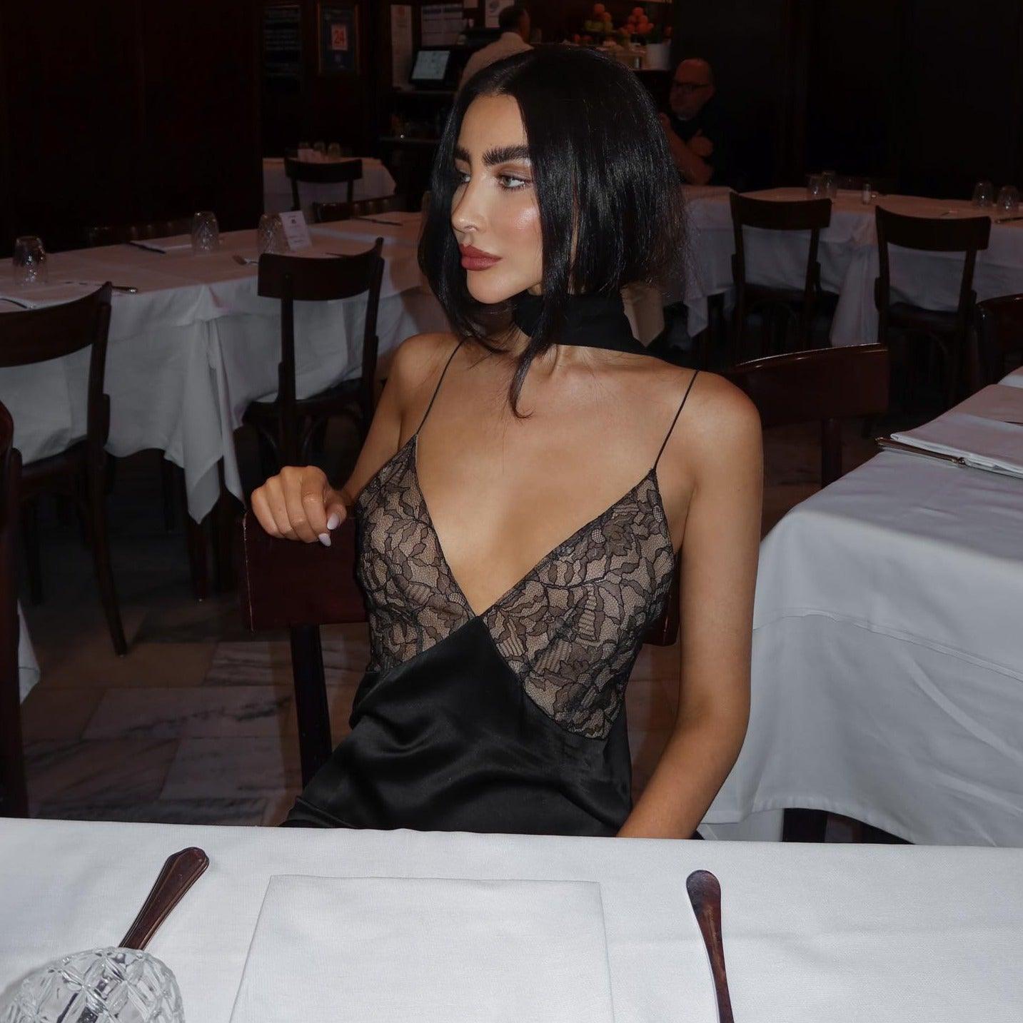 Lace and satin fishtail maxi dress in black with a deep V-neck, worn elegantly for a night out.