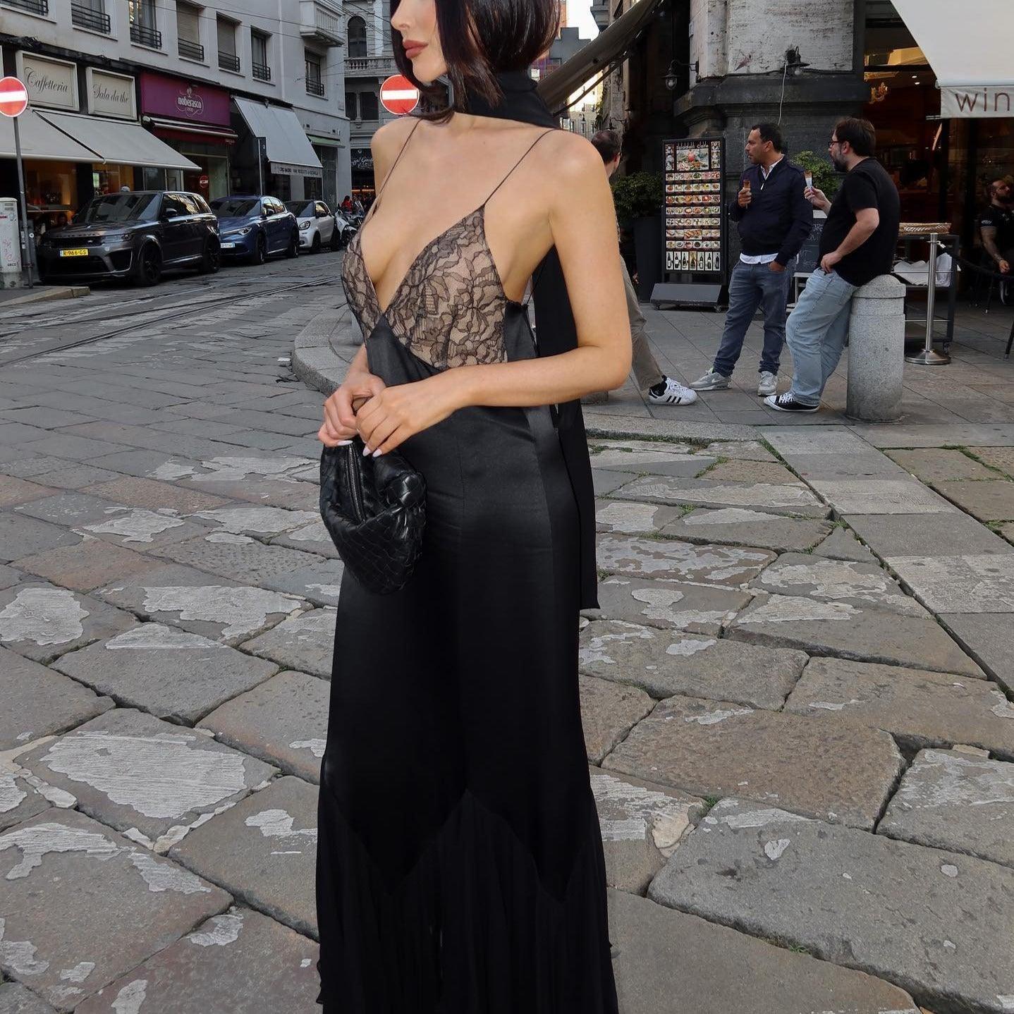 Black satin fishtail maxi dress with lace bodice, deep V-neck, side slit, and chic scarf detail, styled for a night out.