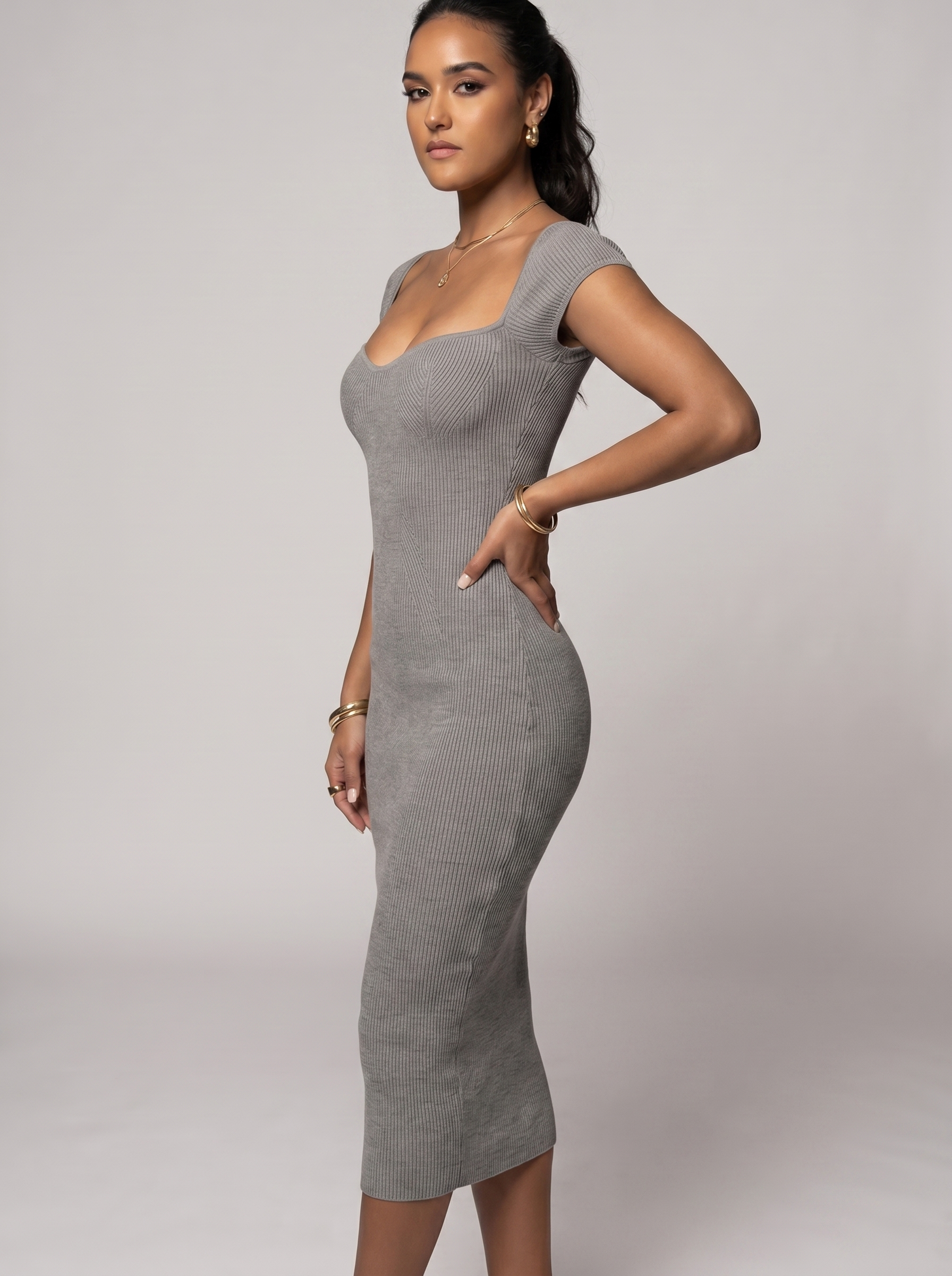 Woman wearing a gray ribbed dress against a plain background