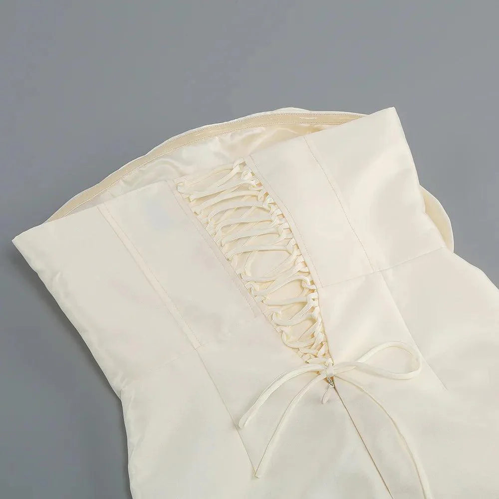 Cream corset mini dress with voluminous flower details, elegantly styled with a lace-up back and tied waist.