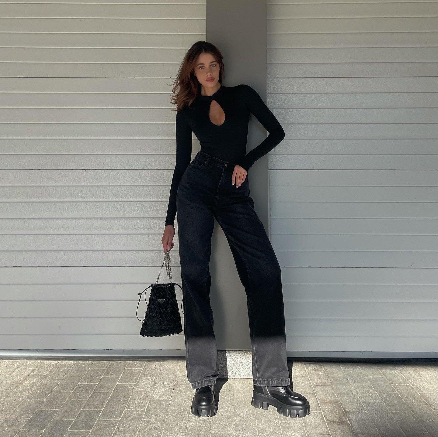 Black long sleeve bodysuit featuring a keyhole neckline, paired with high-waisted black jeans and platform boots.