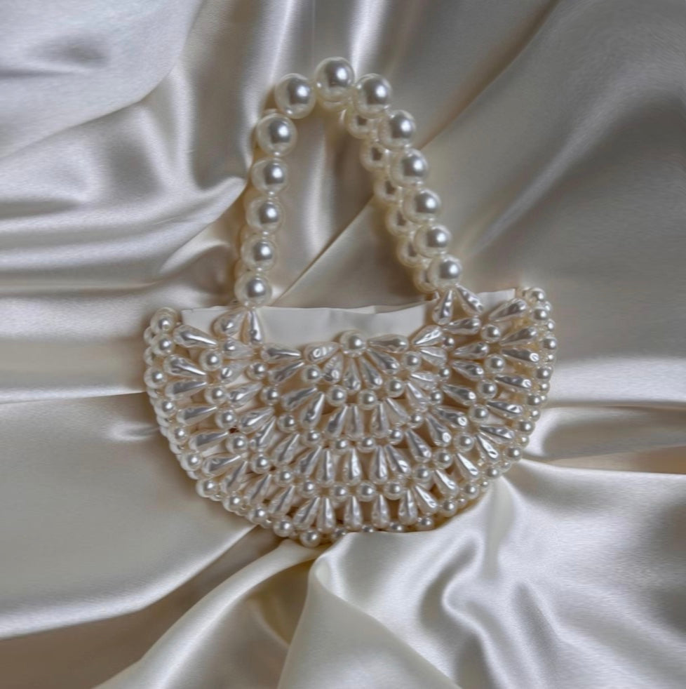 Pearl-handled handbag on a white satin background