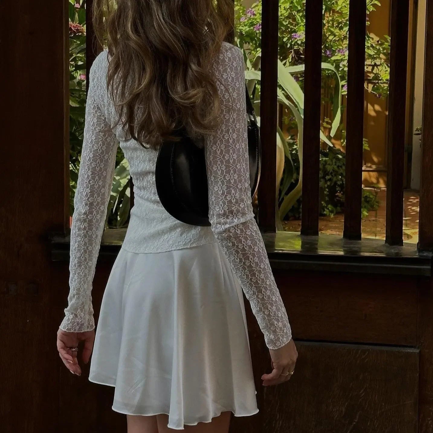 White floral lace trim top with long sleeves, worn with a flared skirt for a feminine, casual look.