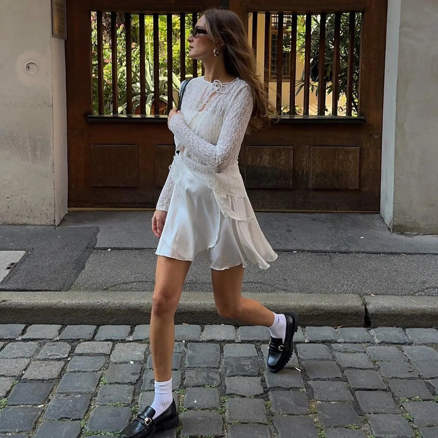 White floral lace trim top with long sleeves, styled with a flowing skirt and casual accessories for an elegant look.