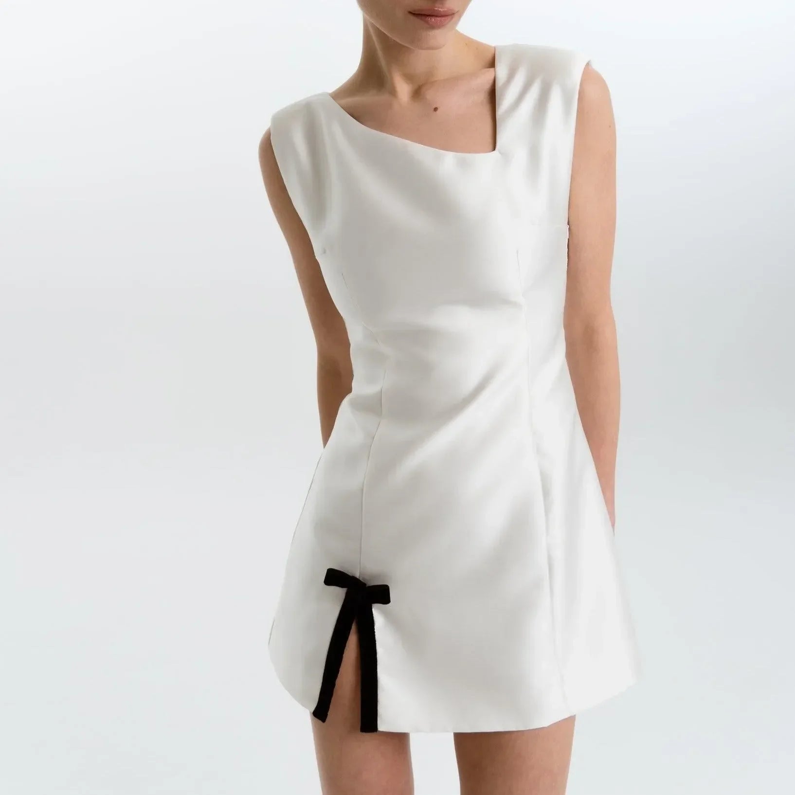 White satin mini dress featuring a square neckline, fitted silhouette, and a side slit with a bow detail. Perfect for...