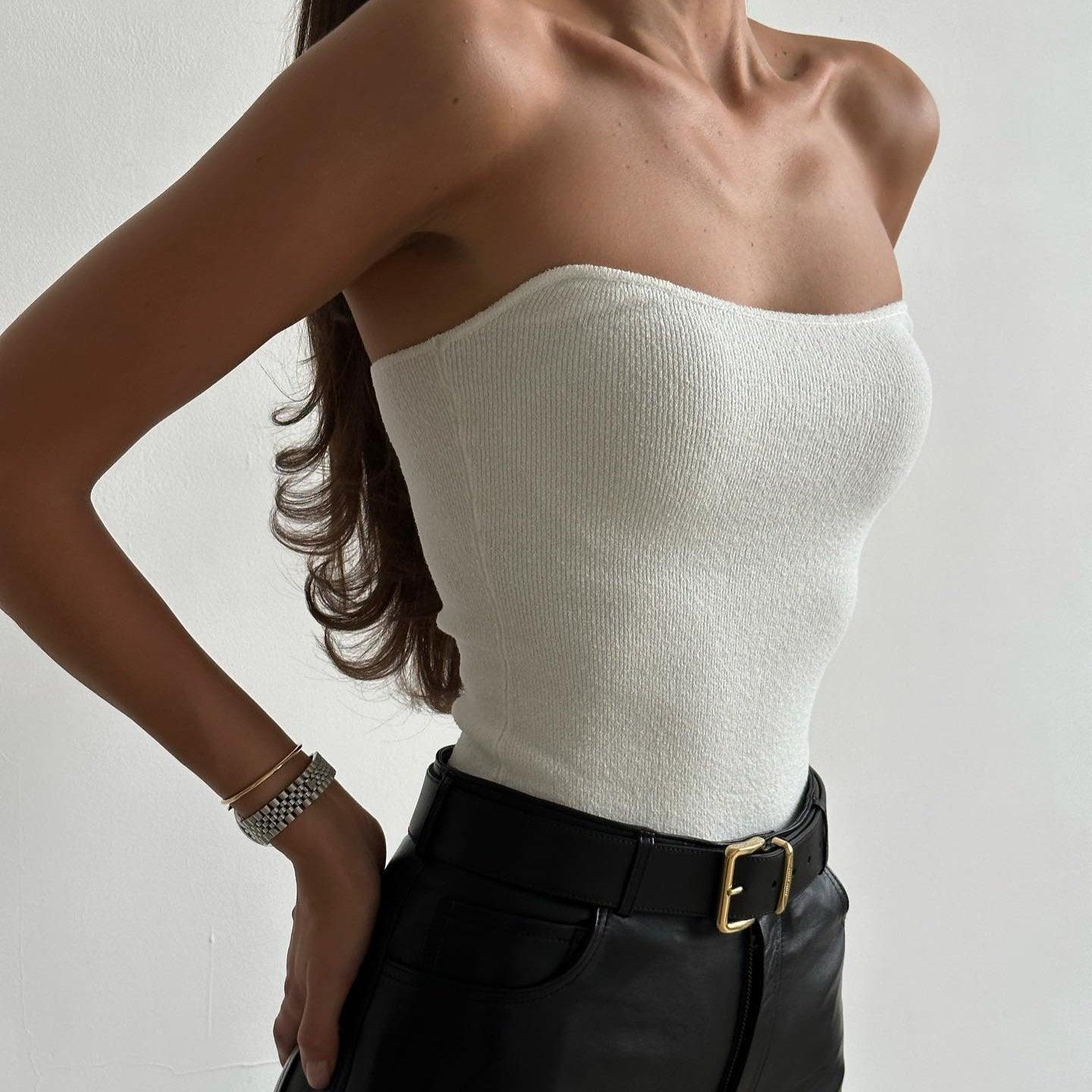 White knitted tube top with a fitted silhouette, styled with high-waisted black leather pants for a chic summer look.