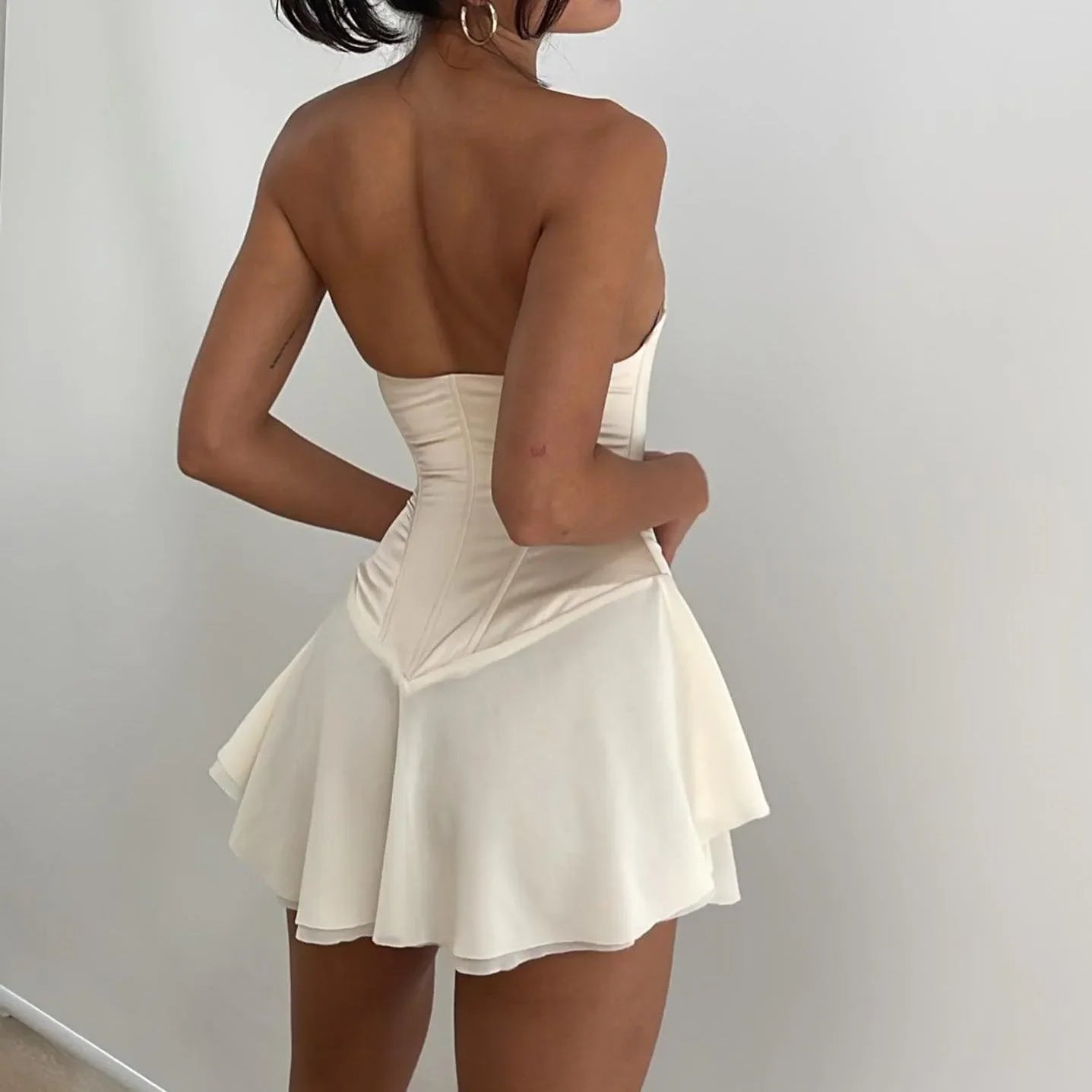 Light cream lace-up corset mini dress with a flared skirt, styled strapless for a trendy, feminine look.