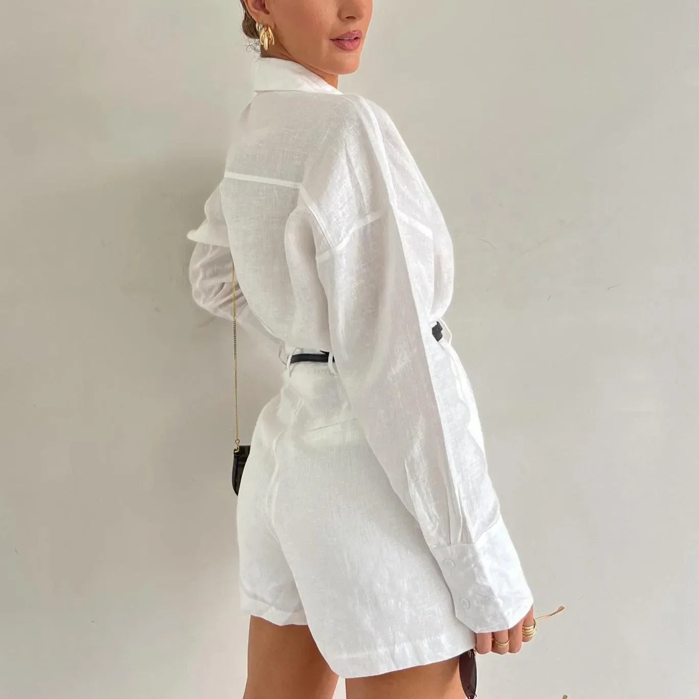 White linen two-piece set featuring a relaxed button-up top and tailored shorts, styled with a belt for a chic look.