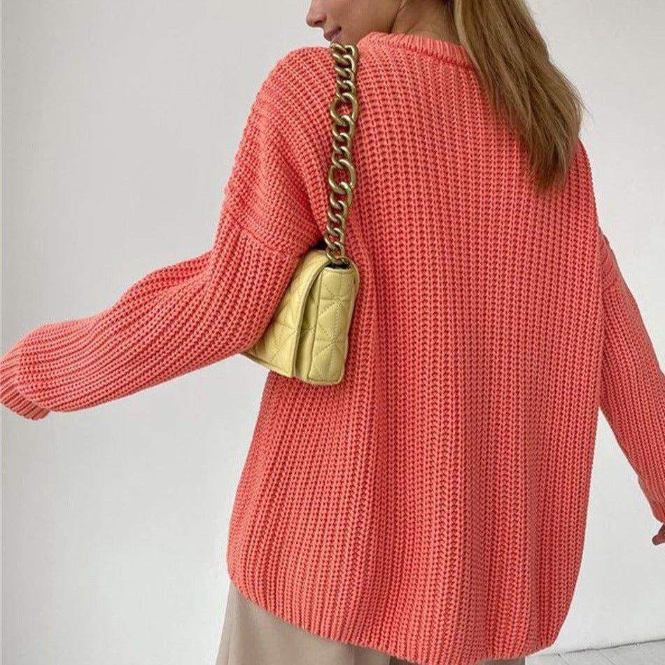 Person wearing a coral knitted sweater with a gold chain bag over their shoulder on a plain background
