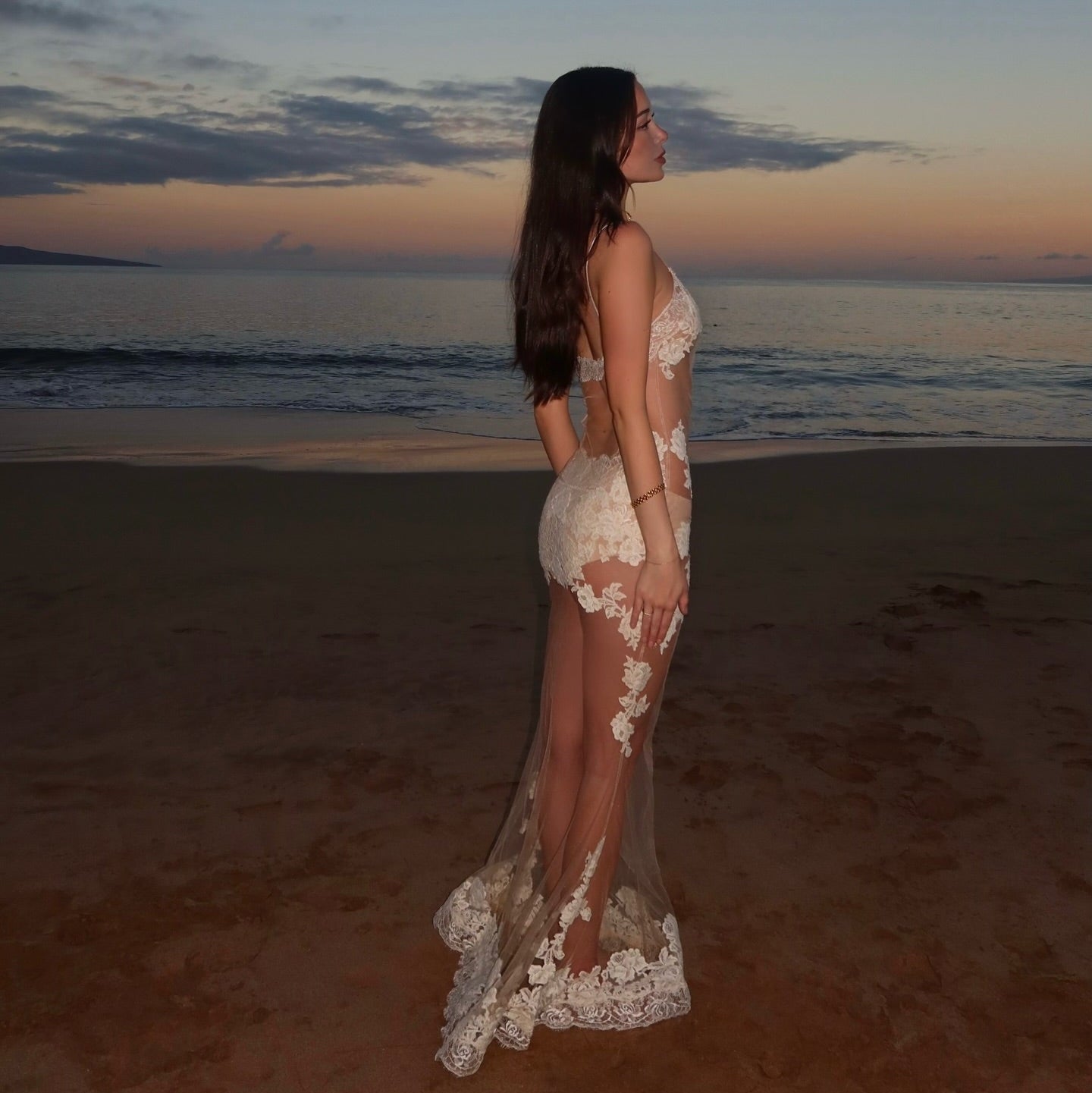 White lace mesh maxi dress with floral details, worn with a sultry silhouette, perfect for evening beach events.