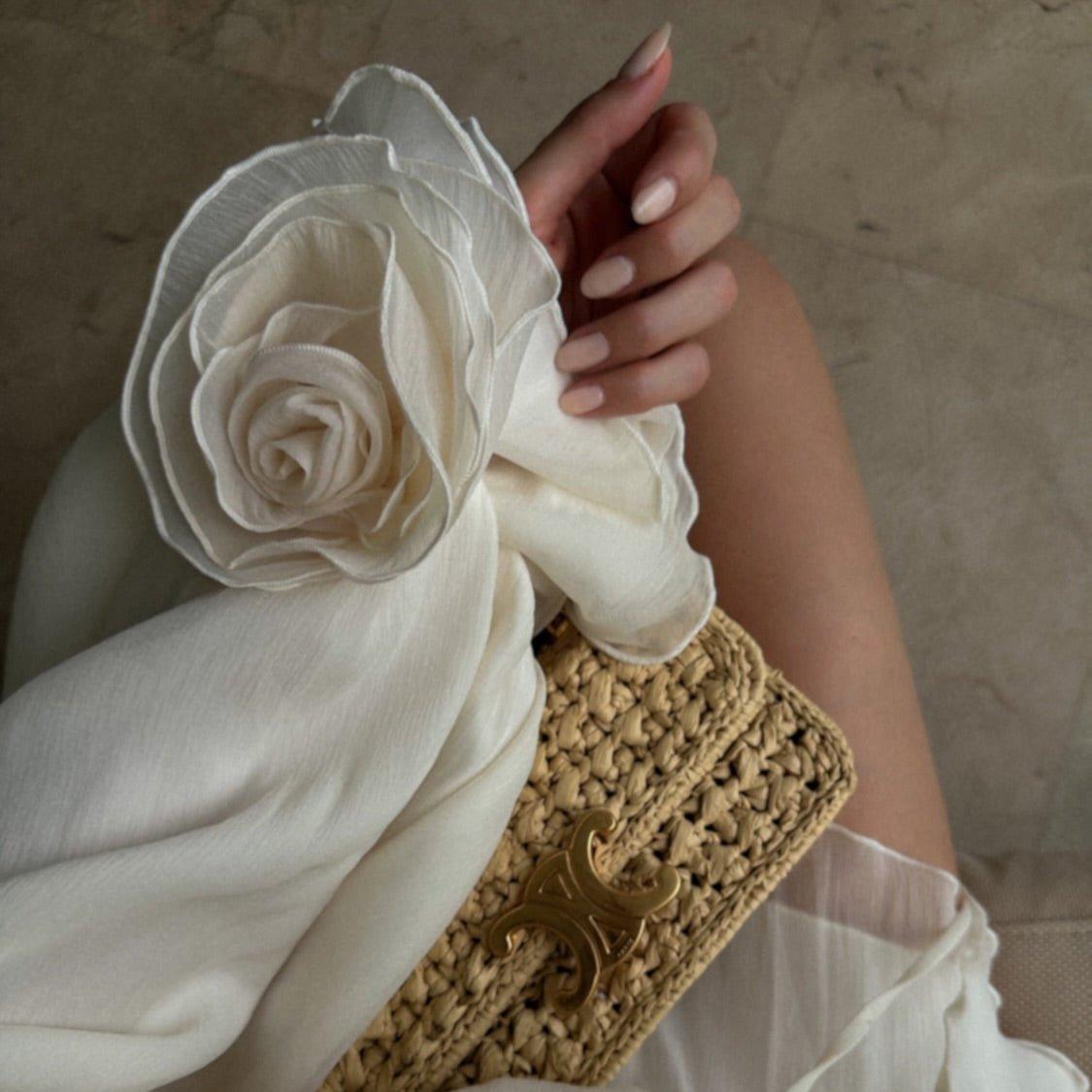 Ivory off-shoulder mini dress with lace-up detailing, styled with a matching floral accessory and woven clutch.