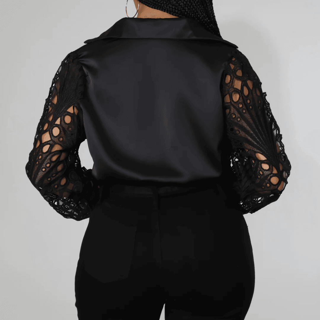 Elegant black blouse with lace sleeves, featuring a satin body and a structured collar, styled with fitted pants.