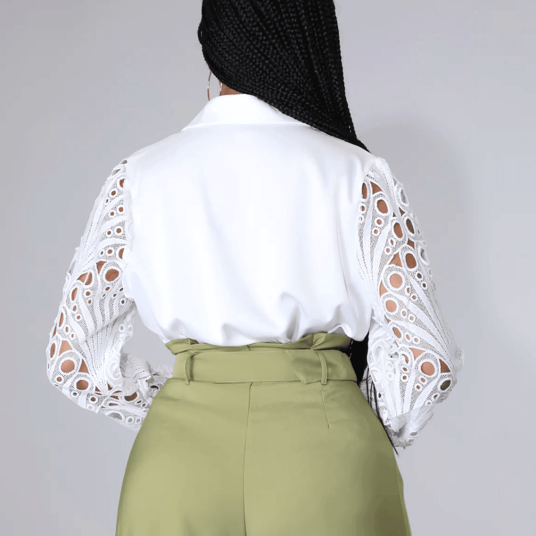 White blouse with lace sleeves and a tailored fit, styled with high-waisted trousers for a chic look.