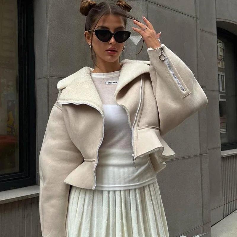 Beige lambswool lapel jacket with a cropped fit, styled over a white top and long, pleated skirt, perfect for a chic look.