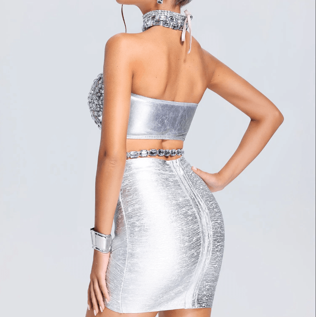 Shiny silver halter crop top with crystal detailing, paired with a fitted metallic mini skirt for a chic, party-ready look.