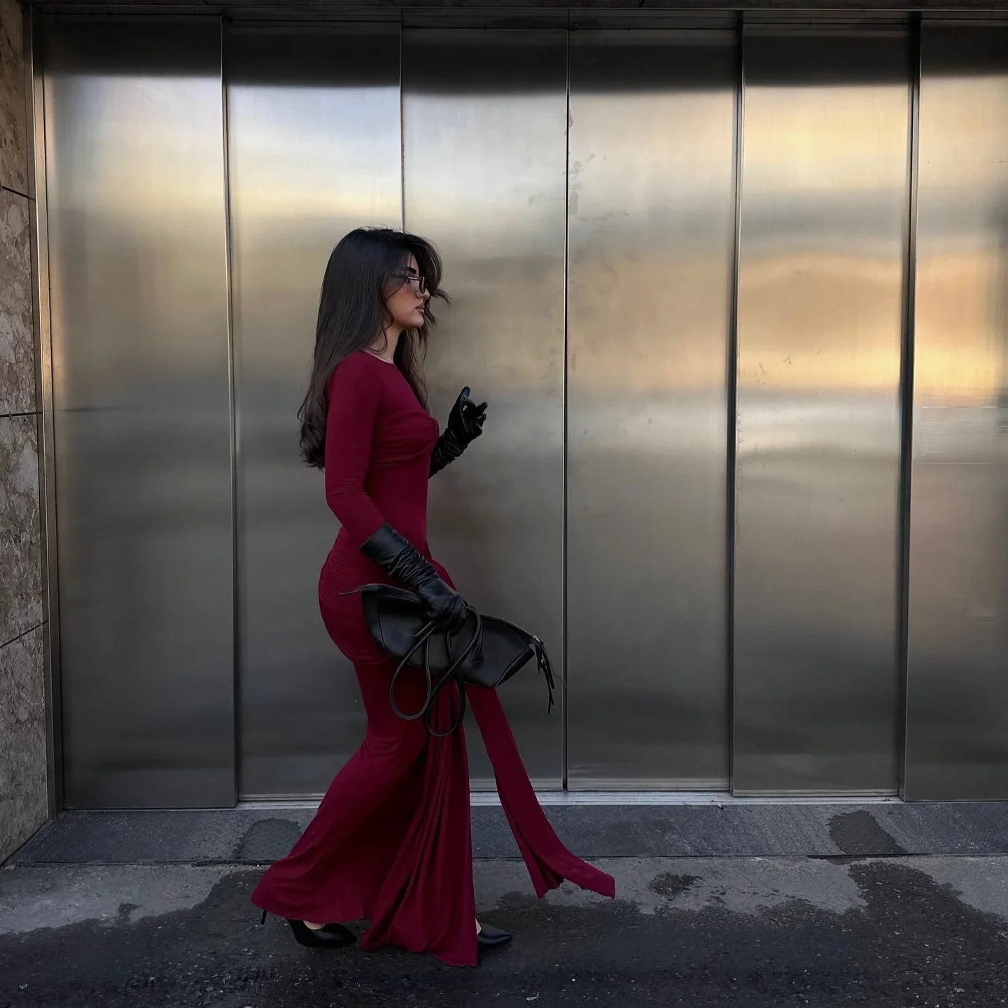 Burgundy long-sleeve maxi dress with black gloves and bag, evening look.