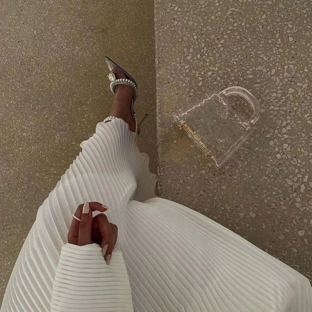 pleated maxi dress with long sleeves, paired with pearl-embellished heels and clear acrylic handbag
