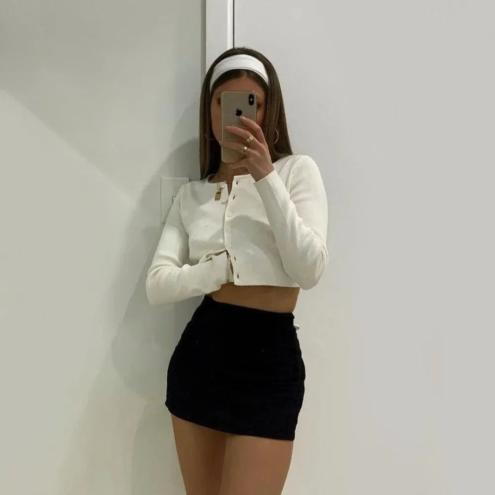 white cropped cardigan with button front, paired with black mini skirt
