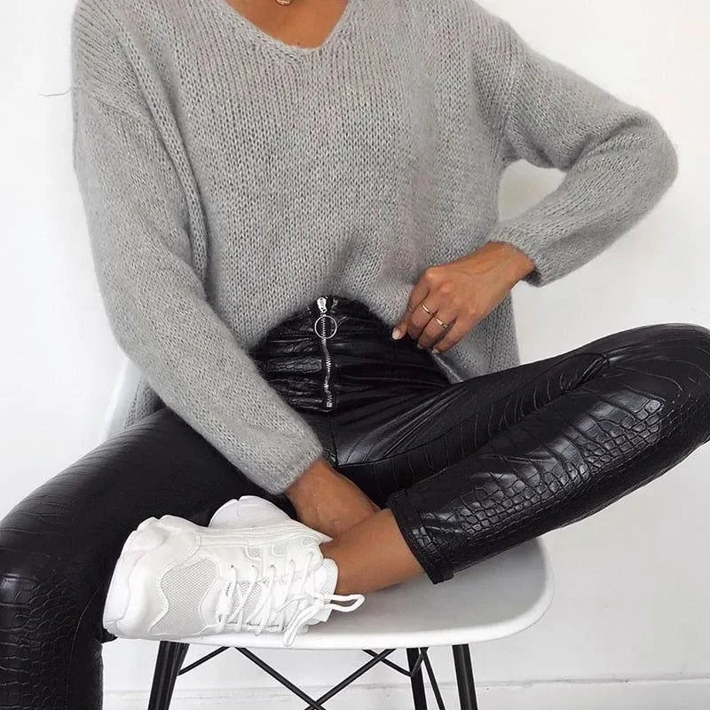 Knit oversized sweater paired with textured leather leggings and white sneakers.