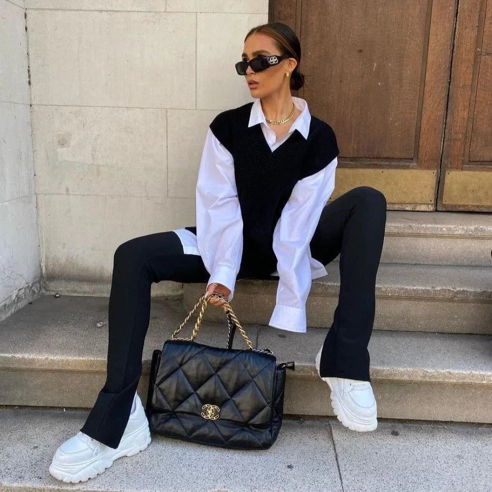 oversized white shirt with black knit vest, paired with flared trousers and chunky sneakers, casual