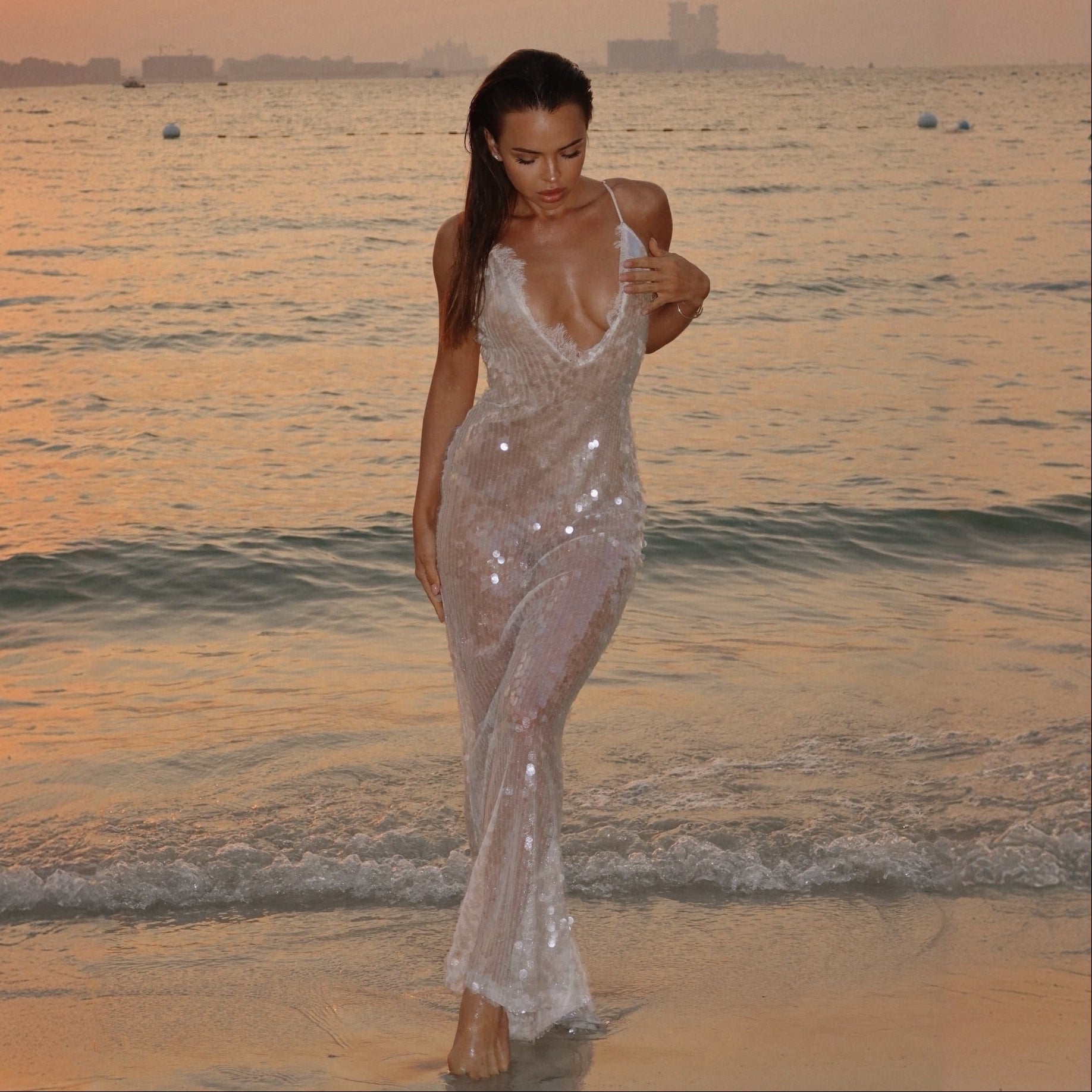 Woman in a sparkly dress walking on a beach at sunset