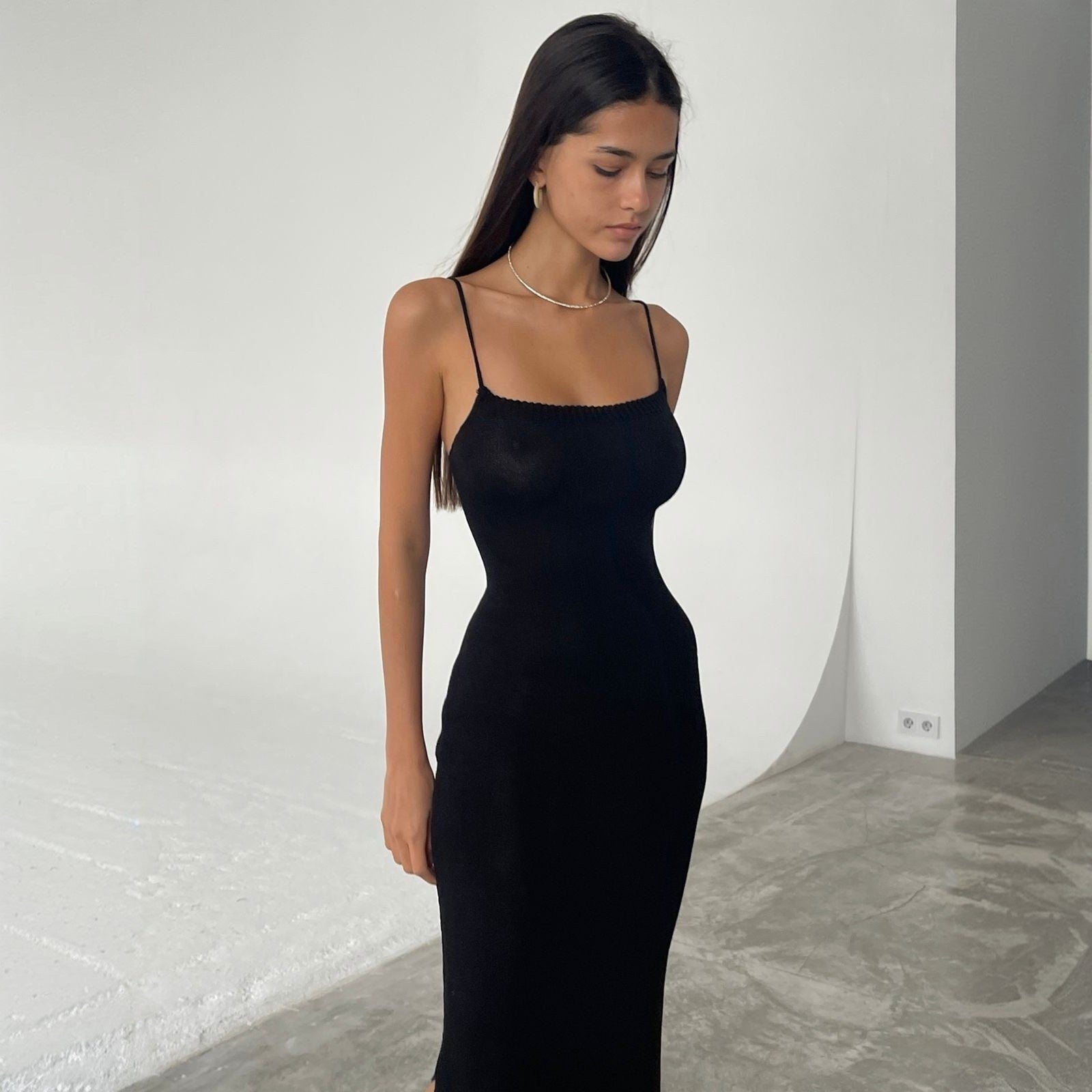 Woman wearing a black dress against a white wall
