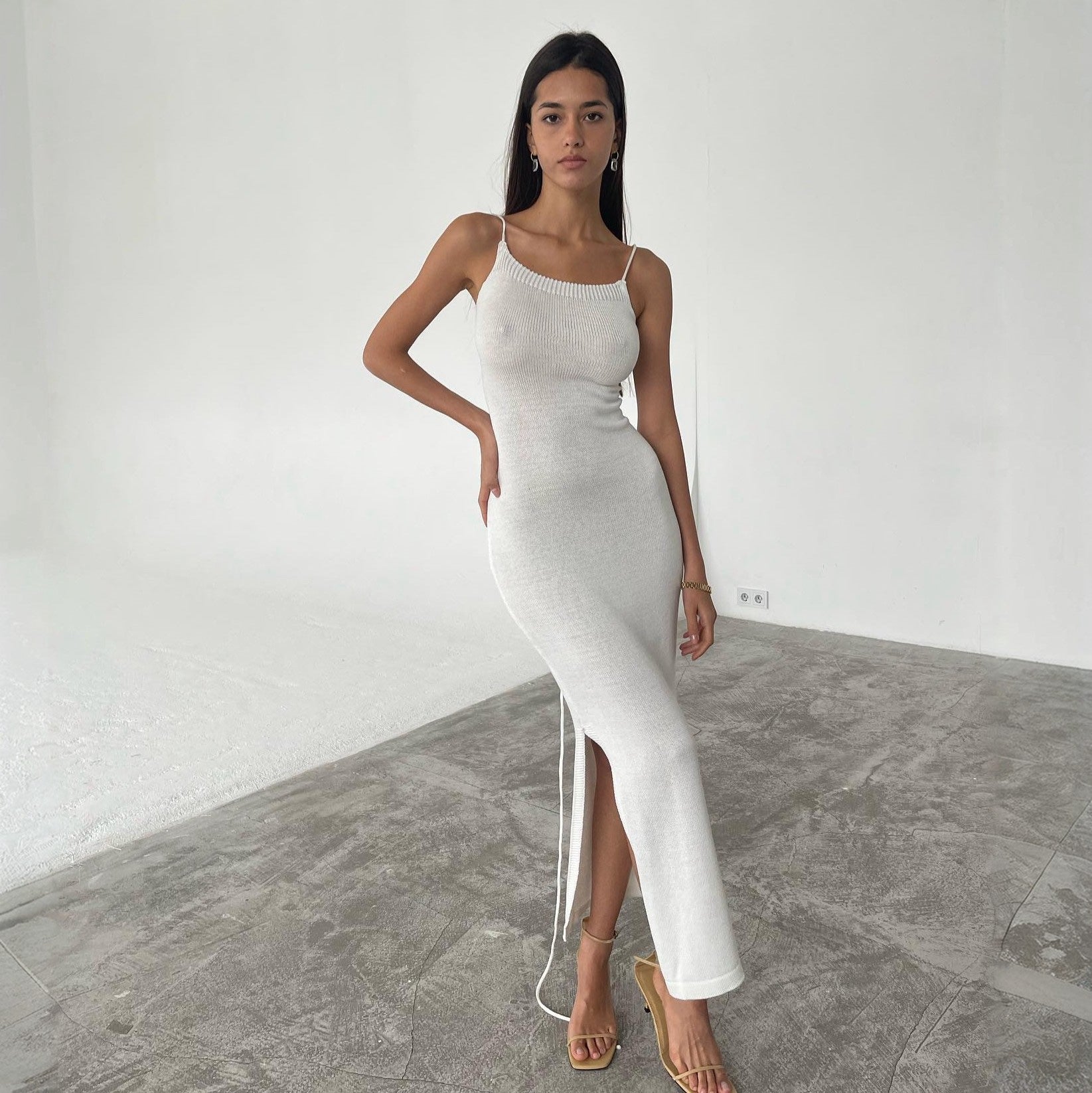 Woman wearing a white dress with a high slit on a neutral background
