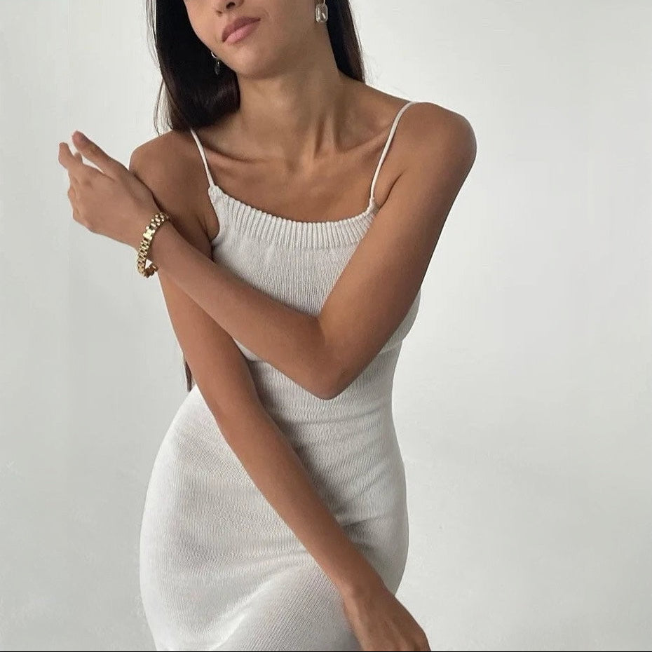 Woman wearing a light gray knit dress against a plain background