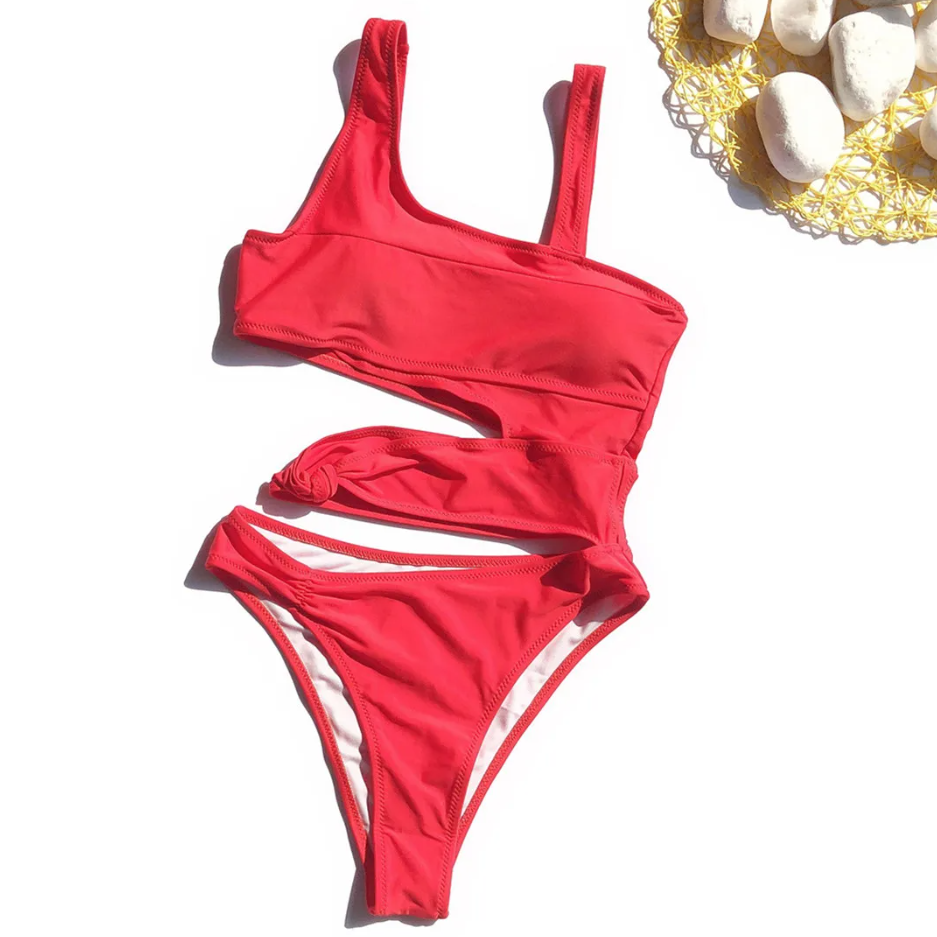 Red bikini set on a white background with decorative stones.