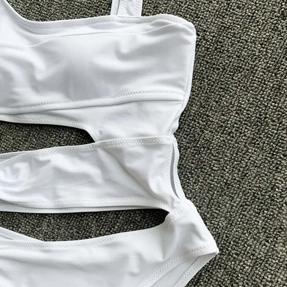 White swimsuit top on a textured gray surface