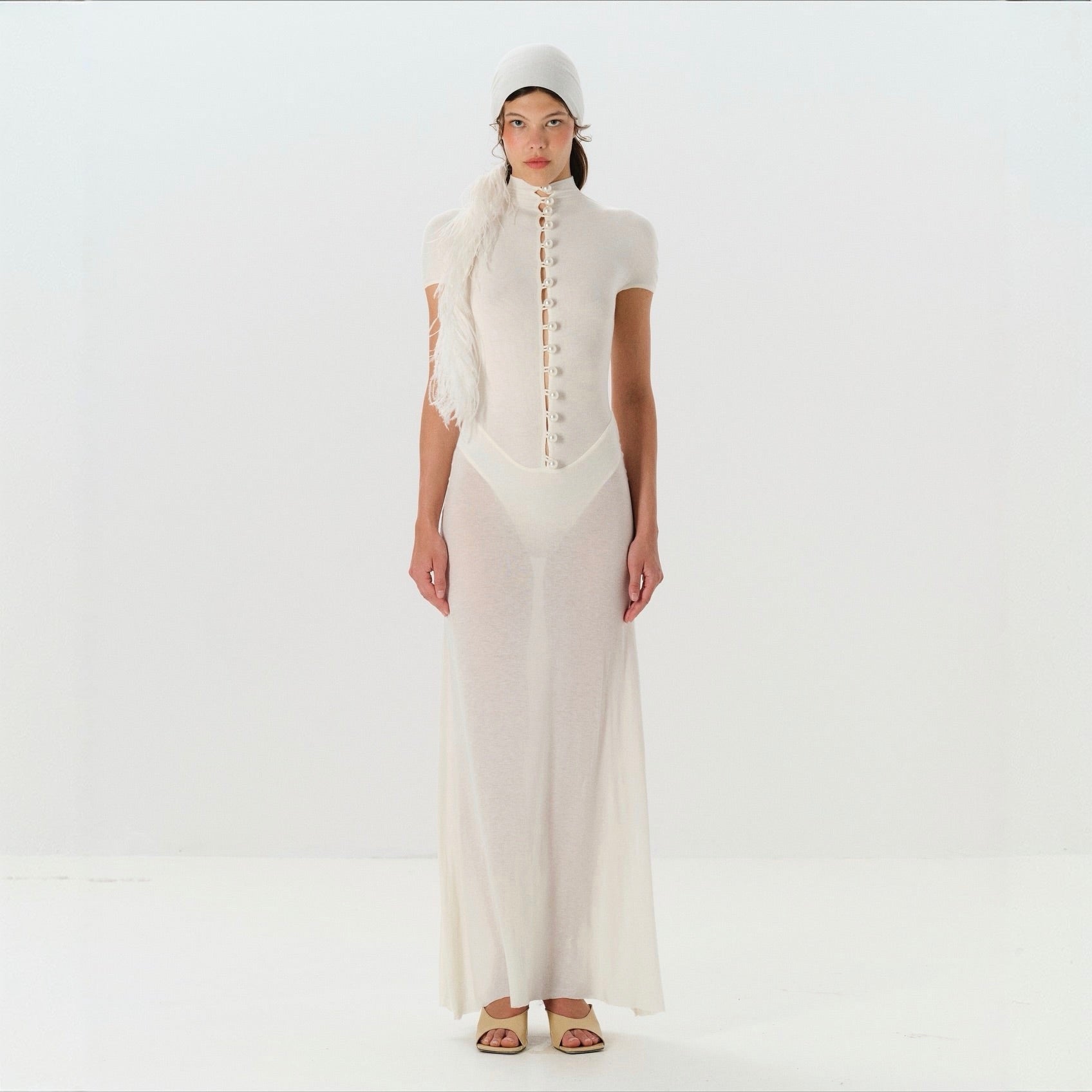Woman wearing a white outfit with a long dress and matching headscarf on a white background