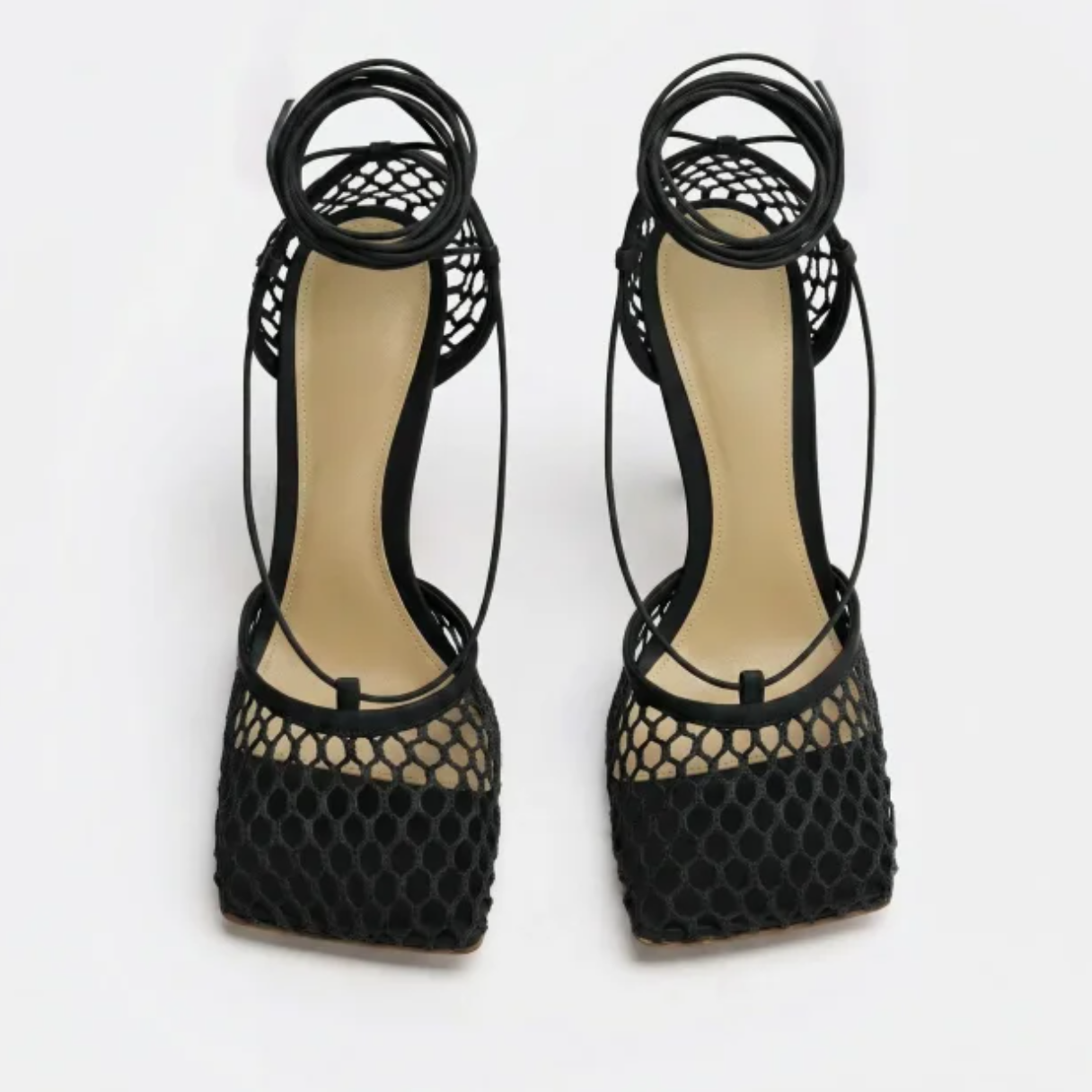 Black high-heeled shoes with fishnet design on a white background