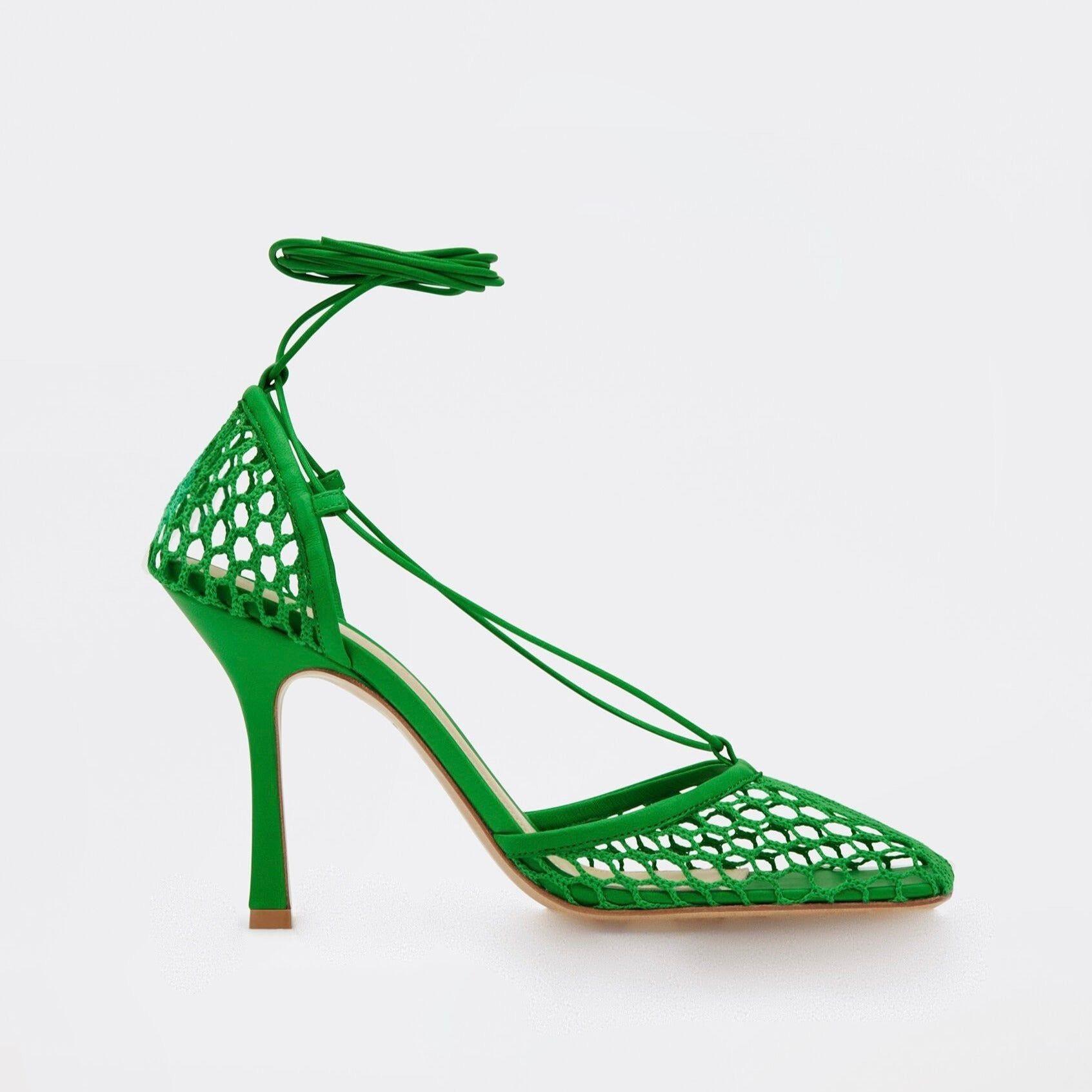 Green high-heeled shoe with cut-out design on a white background
